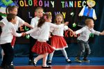 Scena - dzieci w białych koszulkach, dziewczynki noszą czerwone spódniczki, trzymające się razem za ręce w dynamicznym tańcu