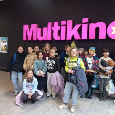 Dzieci z gminy Świdnica w kinie - nad nimi fioletowy neon z napisem Multikino
