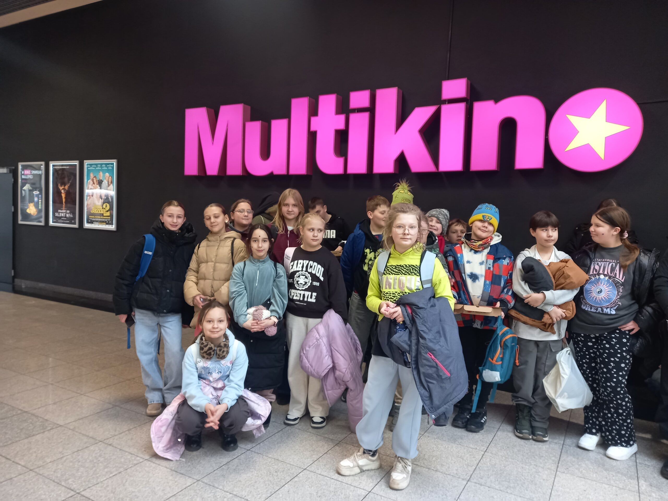 Dzieci z gminy Świdnica w kinie - nad nimi fioletowy neon z napisem Multikino